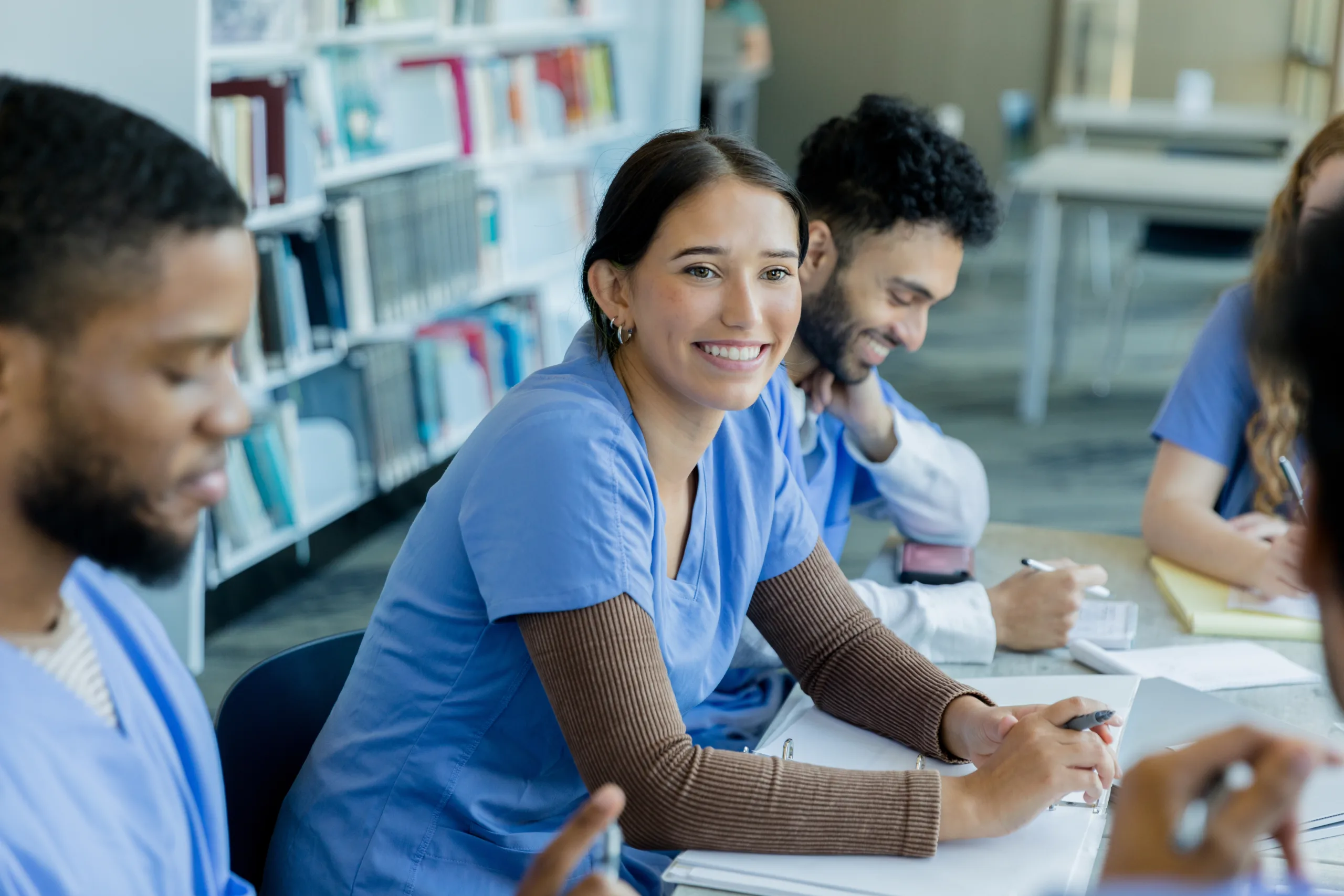 While studying for their medical school exams, fellow students smile as their two classmates discuss ideas.